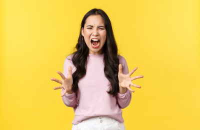 lifestyle emotions advertisement concept mad distressed korean girl losing temper feeling angry overwhelmed screaming shaking hands aggressive standing yellow background